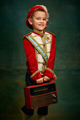 One cute little boy dressed up as medieval little prince and pageboy having fun over dark vintage...