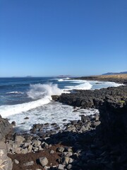 Fototapeta na wymiar Ocean view background. Water splash from waves on rocky beach. Lanzarote island vertical wallpaper.