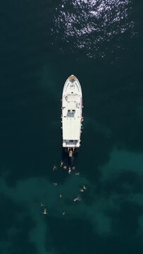 Vertical aerial view of people swimming near a boat on Capri Island, Naples, Italy.