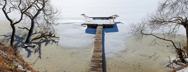 Winter. Bridges or a place for fishing made of wood on stilts. River ice. Sunny and frosty day
