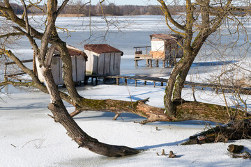 Winter. Bridges or a place for fishing made of wood on stilts. River ice. Sunny and frosty day