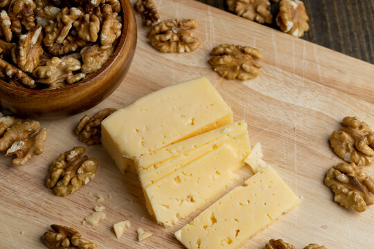 Sliced hard cheese with holes and walnuts