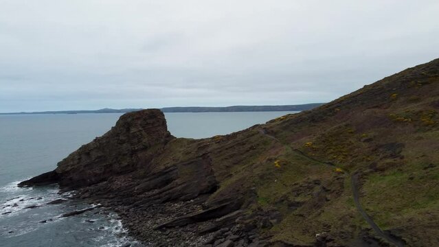 Hiker Walking Along Coast Path with Rickets Head and Dramatic Coastline and Crashing Waves Pembrokeshire UK 4K