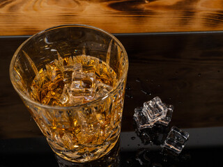 A glass of cognac with ice cubes. A glass of whiskey or bourbon with ice. Close-up.