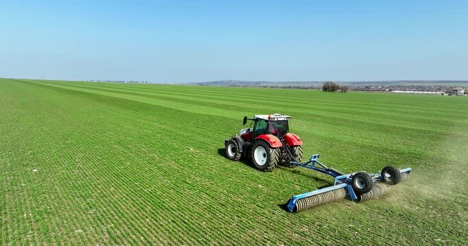 Tractor with a roller tillage on spring field, aerial 4k video. Soil rolling supports germination and is the basis for good harvesting