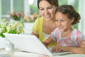 portrait of mom and daughter using laptop