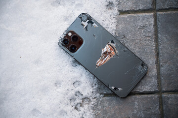 Broken back glass of smartphone fallen on ground.