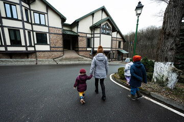 Family walking on path near wooden cottage in the forest. Country house.