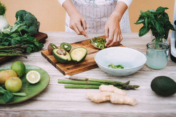 Young woman preparing healthy detox juice with vegetables and fruits - Focus on right hand