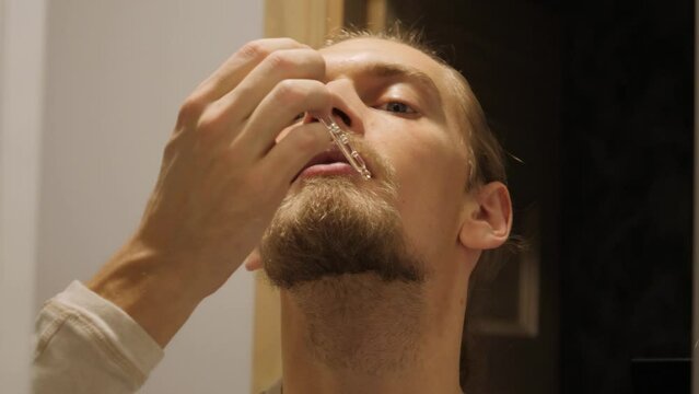 Man apply beard oil with pipette and rub it in.