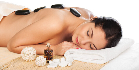 Stone massage for a young beautiful woman at a beauty spa salon.