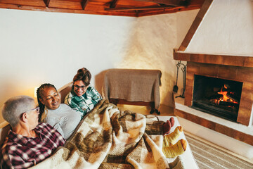 Obraz na płótnie Canvas Multiracial friends having fun in front of cozy fireplace at home - Soft focus on african woman face