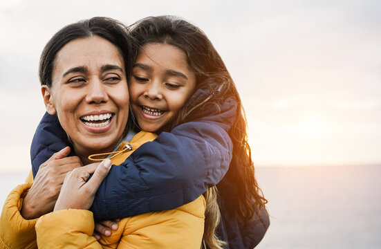 Happy latin mother and daughter having fun together during winter time - Mom day concept - Focus on girl face