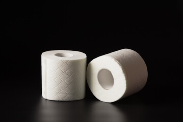 Rolls of toilet paper for personal hygiene on a black background.