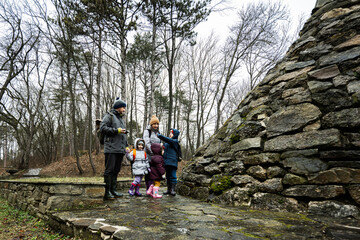 Obraz premium Family tourist with three children, stand near stone monument in forest.