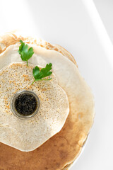served pancake with black caviar, parsley