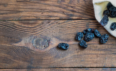 dry grapes on a wooden table. Background with raisins. Raisins on a wooden background fell out of a canvas bag
