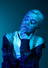 Abstract techno photo. Portrait of young blonde girl with neon stripes on face posing over dark background in blue neon lights. Concept of art, modern style, cyberpunk, futurism and creativity