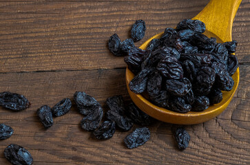 dry grapes on a wooden table. Background with raisins. Raisins on a wooden background and in a wooden spoon.