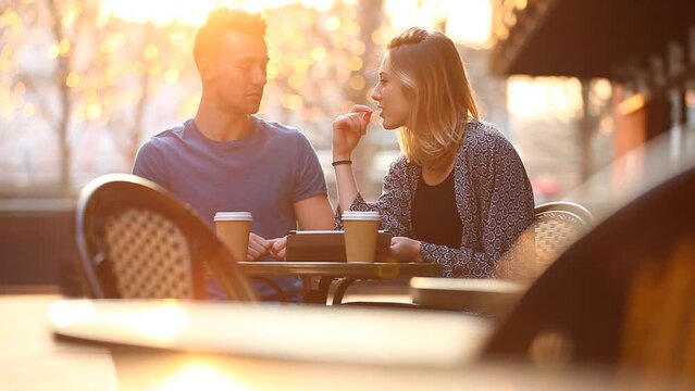 Happy young couple having a coffee together and looking at a digital tablet
