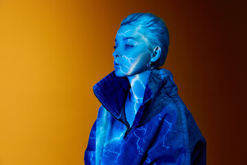 Lightning. Portrait of young blonde girl with abstract neon stripes on body posing over orange...