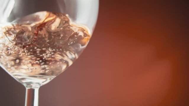 Close up of of rose wine being poured into a glass. Slow motion. 