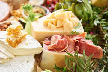 Parmesan cheese with honey close-up. Table full of mediterranean appetizers, tapas or antipasto. Assorted Italian food set. Delicious snack on party or picnic time. Italian style banquet. 