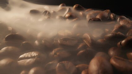 Slider shot of coffee beans during roasting. Smoke comes from fresh coffee seeds. Roasting coffee beans with smoke on dark background