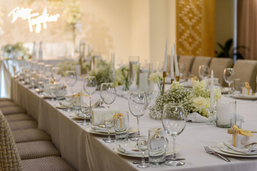 Table setting. Wedding banquet decoration in hall restaurant. Wedding setup. Luxury wedding reception. Festive arch decorated composition flowers and candles. Table covered a tablecloth in party area.