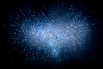 Beautiful blue fireworks display lights up the sky with dazzling display during New Year celebration. Abstract colored fireworks background with copy space. Celebration and anniversary concept