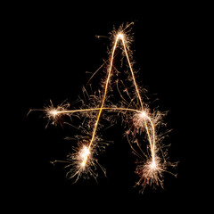 Sparkling burning creative letter A isolated on black background. Beautiful glowing golden overlay object for design holiday greeting card. Creative lettering A written with burning sparklers