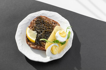 Black caviar on a sandwich with eggs, lemon, greenery