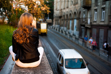 Fototapeta premium Smiling woman in the city street wearing black leather jacket and white pants and sunglasses