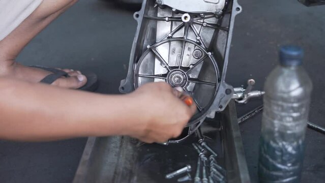 Hands of a mechanic cleaning automatic motorcycle spare parts