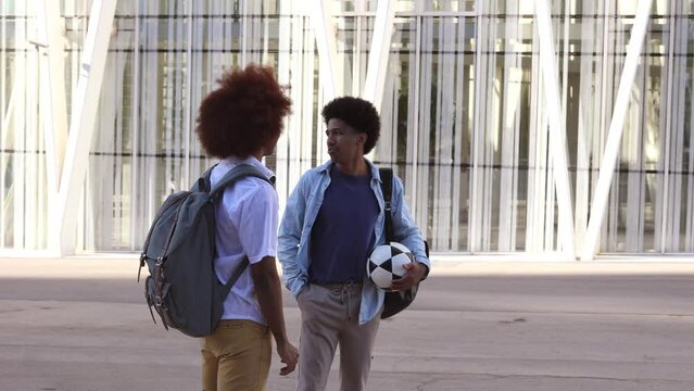 two male friends with a soccer ball talking