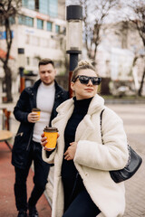 Obraz premium A young couple is walking on the street and enjoying the fresh air. Happy married couple. A stylish couple, a man and a woman. Selective focus