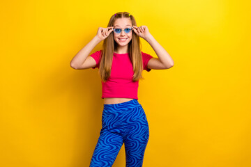 Photo of young cheerful smiling girl teenager wear stylish outfit try new eyeglasses blue specs summertime isolated on yellow color background
