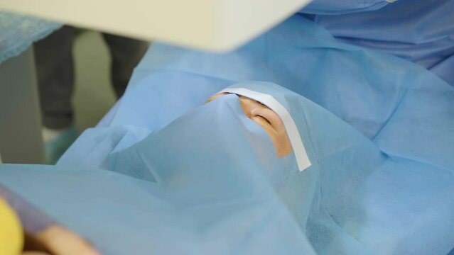 Laser vision correction. A patient and team of surgeons in the operating room during ophthalmic surgery