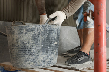 Worker installing new wall tile indoors, closeup. Prepared for renovation