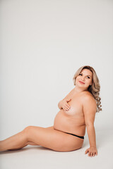 a naked pregnant against the background of a white cyclorama in a photo studio. 