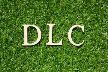 Wood alphabet letter in word DLC (abbreviation of downloadable content) on artificial green grass...