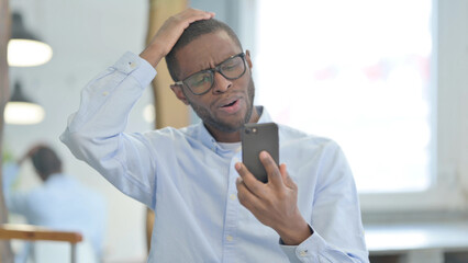 Portrait of African Man with Loss on Smartphone