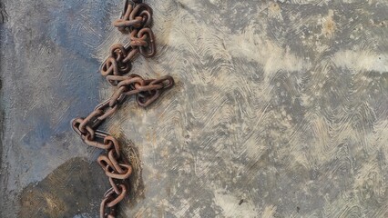 A rusty chain on the wet solid ground after rain