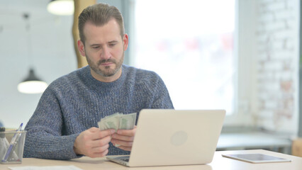Middle Aged Man Counting Dollar in Office