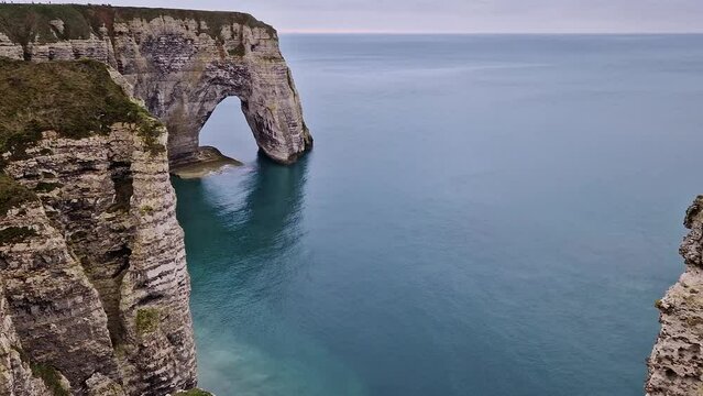 Sightseeing view to the Porte d'Aval natural arch cliff washed by Atlantic ocean waters at Etretat, Normandy, France. Beautiful coastline scenery with famous Falaise d'Aval
