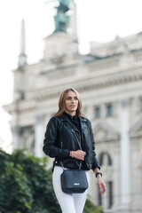 A woman wearing a black leather jacket and sunglasses smiles.