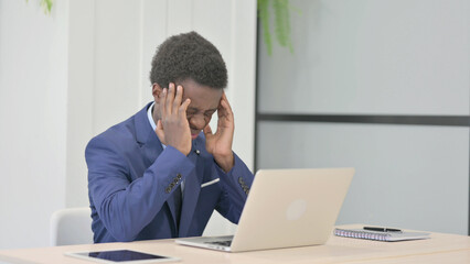 African Businessman having Headache while Working on Laptop