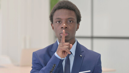 Fototapeta na wymiar Young African Businessman with Finger on Lips, Asking for Silence