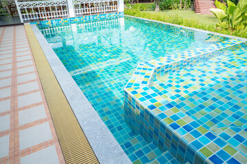 The Macro from Swimming pool with clear blue water in a garden area, surrounded by plants