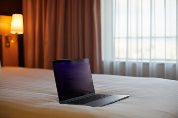 ホテルの客室のベッドと開いたノートパソコンの様子
